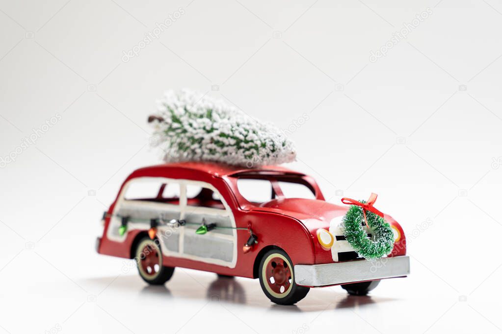 Little red vintage car carrying a Christmas tree on top