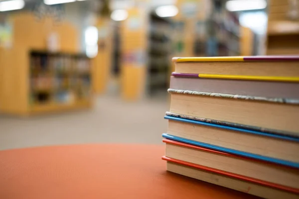 Montón de libros sobre una mesa de madera en una biblioteca — Foto de Stock