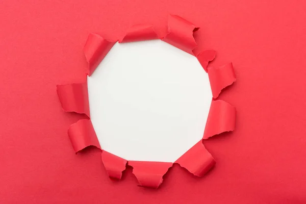 Papel vermelho com buraco rasgado no fundo do meio — Fotografia de Stock