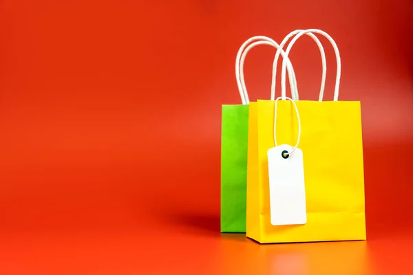 Bolsas de regalo o compras amarillas y verdes aisladas en rojo —  Fotos de Stock