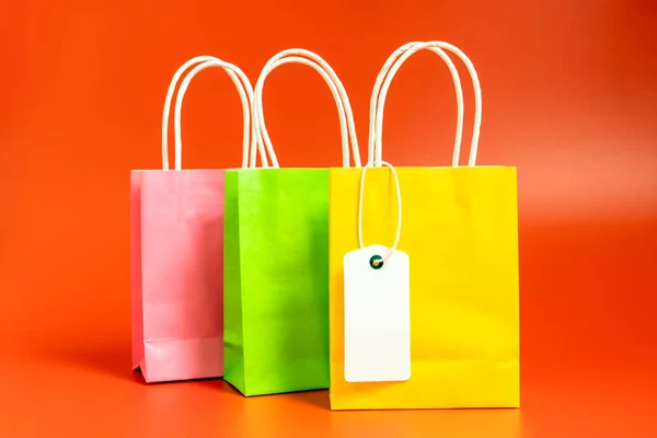 Sacos de compras ou presentes amarelos, verdes e rosa isolados em vermelho — Fotografia de Stock