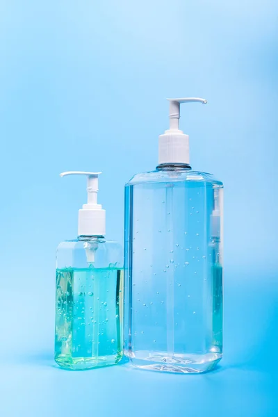 Duas mãos desinfetante em garrafa de plástico no fundo azul — Fotografia de Stock