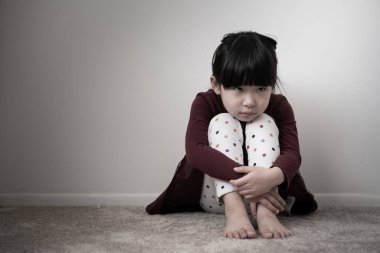 Yalnız üzgün küçük kız dizlerini tutuyor