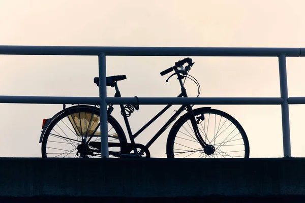 在黄昏的天空映衬下，街头的自行车轮廓 — 图库照片