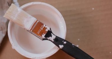 Beyaz duvar boyası kutusunda boya fırçası
