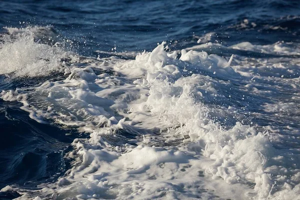 Fale z rozbryzgami piany w wodzie morskiej — Zdjęcie stockowe