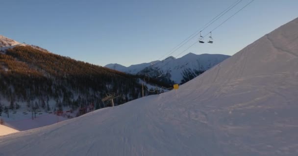 Esquiar por una pendiente la luz del sol que brilla desde la puesta del sol — Vídeos de Stock