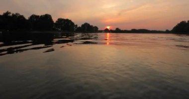 Sakin bir gölün üzerinde gün batımı