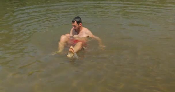 Kerl spielt im Sommer im flachen Wasser — Stockvideo