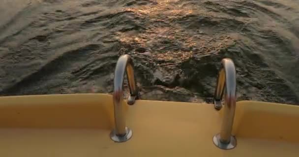 夕阳笼罩在平静的湖面上,浪花倒映在船尾 — 图库视频影像