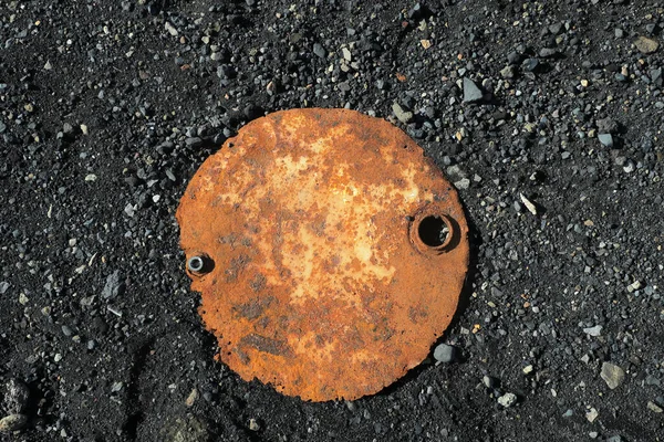 Rostiger Metallschrott auf schwarzem Sand — Stockfoto