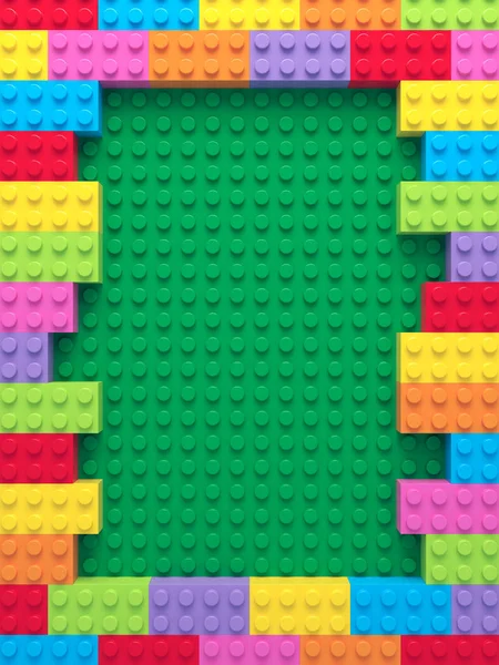 Frame of colorful toy bricks on green construction plate — Stock Photo, Image