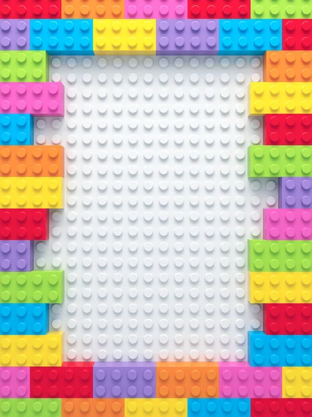 Frame of colorful toy bricks on white construction plate — Stock Photo, Image