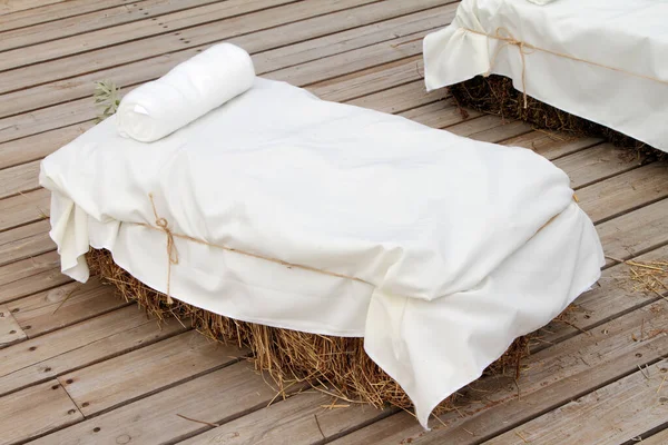 Stylized sofa made of straw bale covered with white fabric.