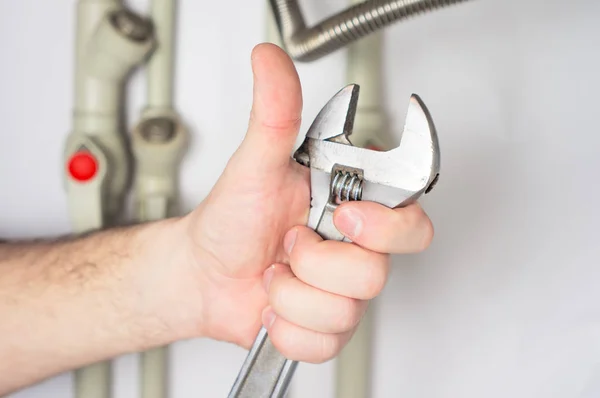 A hand holding a pipe wrench against the background of a gas boi — Stock Photo, Image