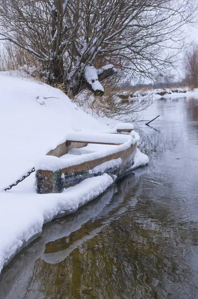 Łodzi drewnianych pokrytych śniegiem, na brzegu rzeki zima — Zdjęcie stockowe