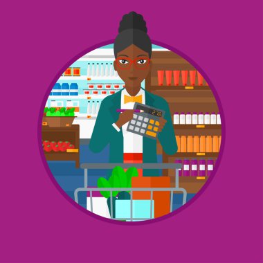 Woman counting on calculator at supermarket.