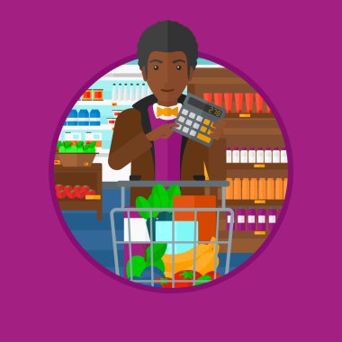 Süpermarkette hesap makinesine güvenen adam.