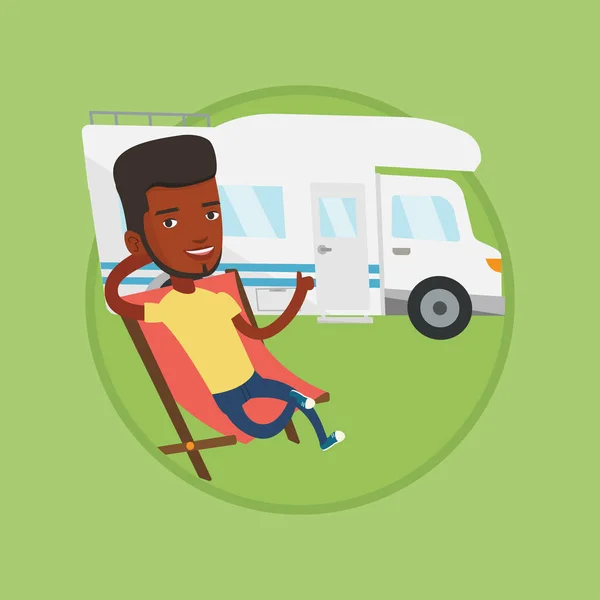 Człowiek siedzi w fotelu przed camper van. — Wektor stockowy