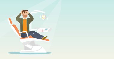 Diş sandalyede oturan korkan adam.