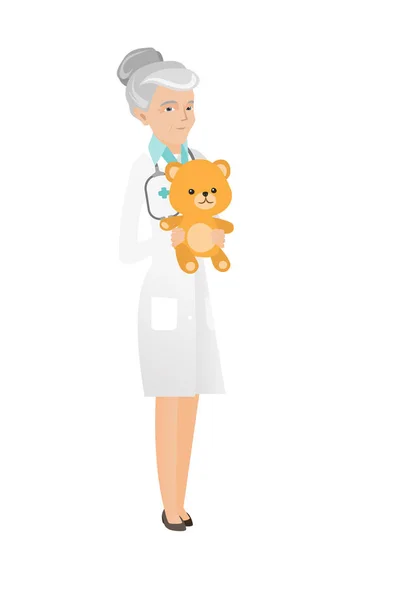 Senior kavkazské pediatra drží medvídek. — Stockový vektor