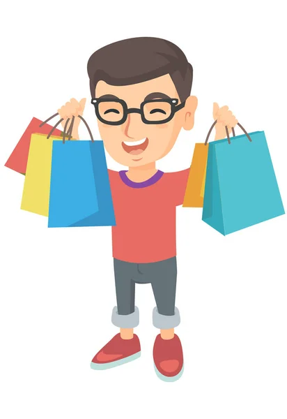 Menino caucasiano feliz segurando sacos de compras . — Vetor de Stock