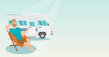 Camper van önünde bir sandalyede oturan adam.