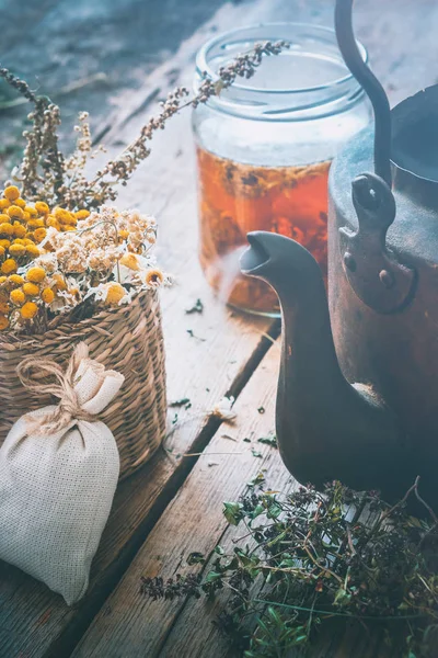 Ervas curativas em cesta, chaleira de chá vintage e jarra de chá saudável . — Fotografia de Stock