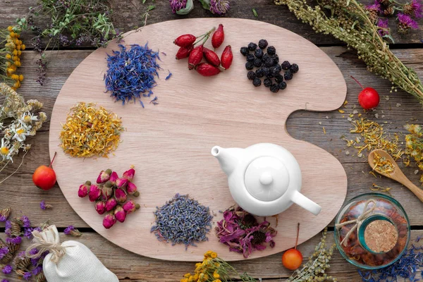 Herbes de guérison sur palette en bois et bouilloire à thé, vue sur le dessus . — Photo
