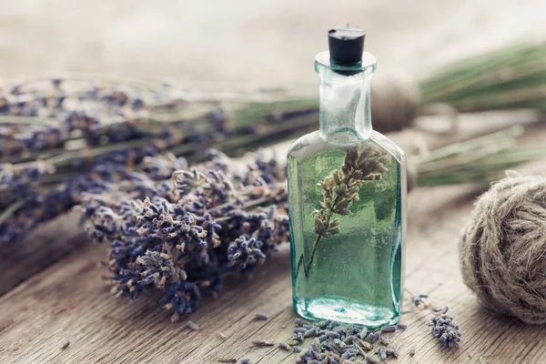 Fles van etherische olie en bos lavendel bloemen op tafel. — Stockfoto