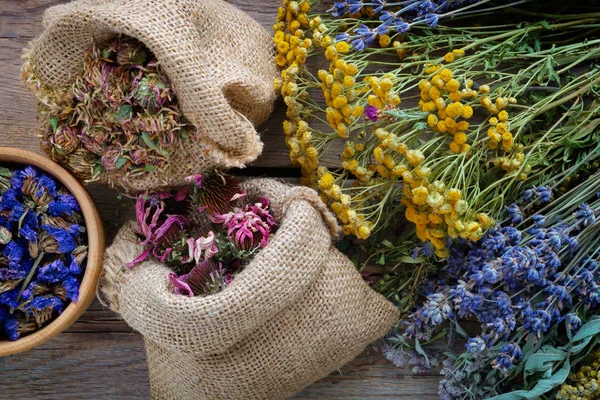 Hierbas medicinales, mortero de madera y dos bolsas de flores sanas secas — Foto de Stock