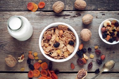 Sağlıklı kahvaltı için malzemeler: tahıl buğday pul tabağı, kurutulmuş meyve ve süt şişesi.