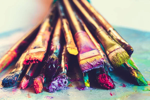 Artist paintbrushes with paint closeup on artistic canvas. — Stock Photo, Image