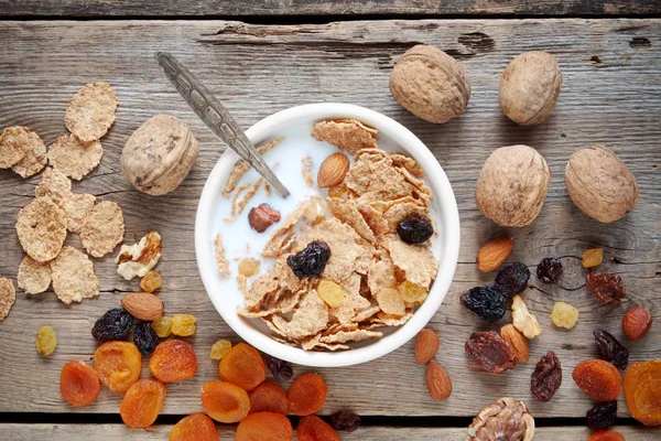 Café da manhã saudável: flocos de trigo de cereais com leite em tigela, frutas secas, muesli e nozes — Fotografia de Stock