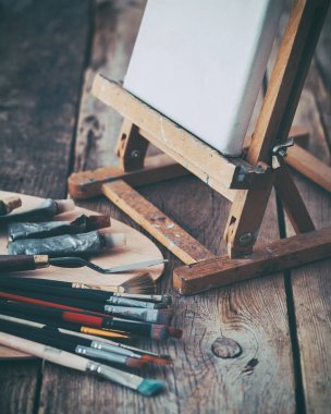 Sanatsal ekipman: beyaz sanatçı tuval üzerine bir sanatçı stüdyoda şövale, palet ve Boya fırçaları. Tonda retro.