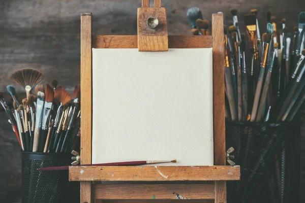 Sprzęt Artystyczny w studiu artysty: artist canvas na drewniane sztalugi i farby pędzle. — Zdjęcie stockowe