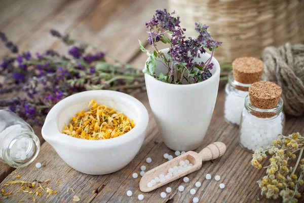 Mortar and bowl of dried healing herbs and bottles of homeopathic globules.  Homeopathy medicine concept. — Stock Photo, Image