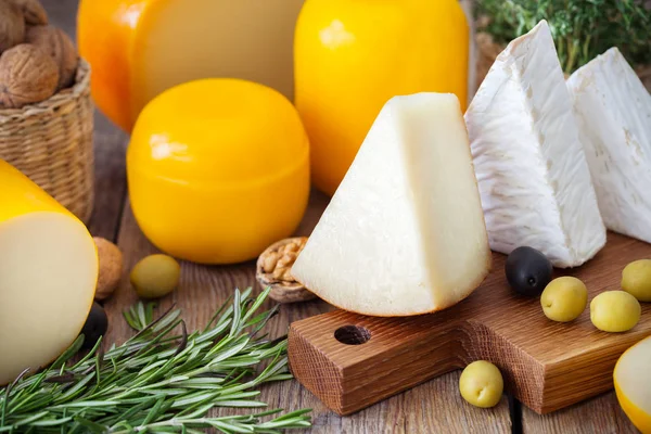 Assorted gourmet cheeses, olives, nuts and rosemary. — Stock Photo, Image