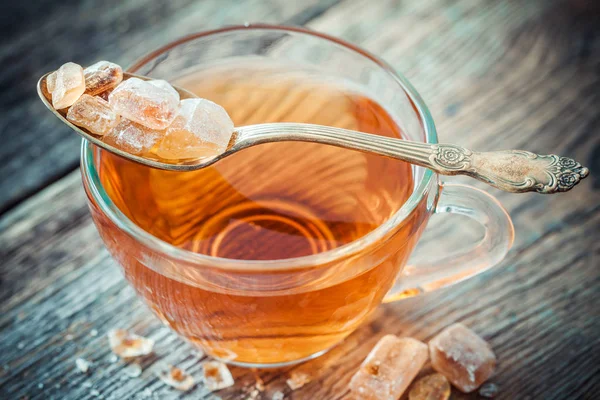 Xícara de chá e açúcar de cana caramelizado na colher . — Fotografia de Stock