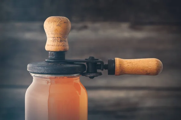 Glass jar of juice and retro can lid closing machine for canning — Stock Photo, Image