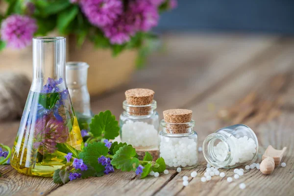 Injekční lahvičky tinktura nebo infuze zdravých bylinek, lahví homeopatie globule a zdravé bylinky na stole. Alternativní medicína koncept. — Stock fotografie