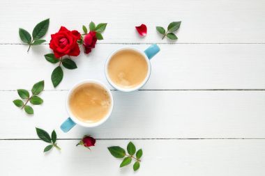 İki espresso kahve fincan ve kopya alanı Beyaz ahşap zemin üzerine kırmızı gül çiçekler. Düz yatıyordu. Üstten Görünüm.