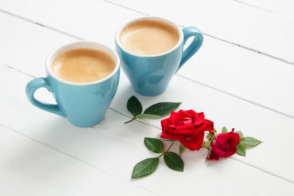 Két kávé espresso csészék és piros rózsa virágok fehér fa háttér, másol hely. — Stock Fotó
