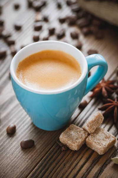 Taza de café expreso, terrones de azúcar, granos de café y especias sobre tabla de madera. Retro estilizado . — Foto de Stock