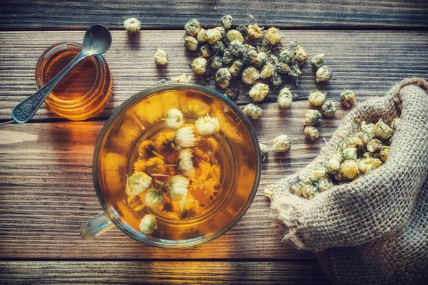 Healthy chamomile tea cup, hessian bag of dry daisy flowers and honey jar. Top view. — Stock Photo, Image