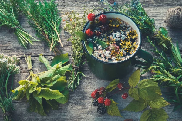 Chá de ervas saudável em caneca esmaltada e cachos de ervas curativas. Medicina herbácea. Retro tonificado . — Fotografia de Stock