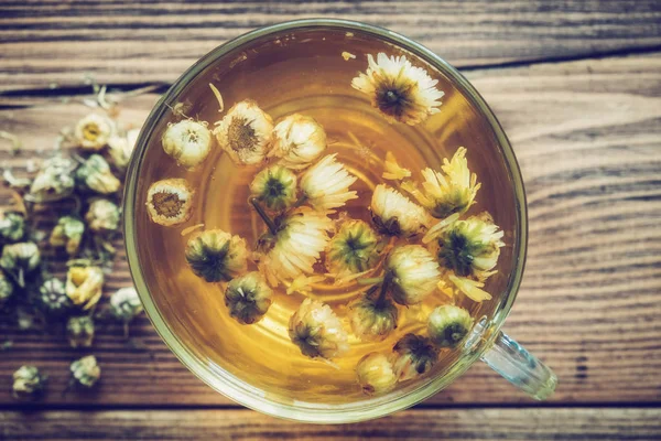Xícara de chá de camomila saudável e flores secas da margarida. Vista superior . — Fotografia de Stock