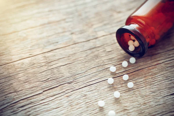 Espalhados glóbulos homeopáticos e garrafa em fundo de madeira. Homeopatia medicina . — Fotografia de Stock
