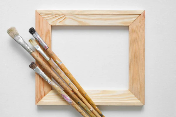 Trä båren bar och penslar på vita artist canvas bakgrund. Ovanifrån. Kopiera utrymme för text. — Stockfoto