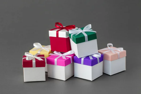 Mehrere bunte Geschenkboxen mit Bändern auf grauem Hintergrund. — Stockfoto